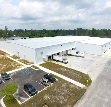 long shot of a warehouse with trucks and cars out front